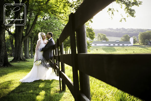 Bride and groom with fence and barn at Warrenton VA farm wedding